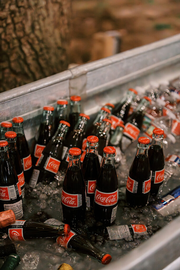 under the oaks, texas wedding venue, wedding rehearsal, texas bride, one more night, shiner texas, oak trees, bistro lights, dinner set up, outdoor dinner set up, coke, glass bottle coke