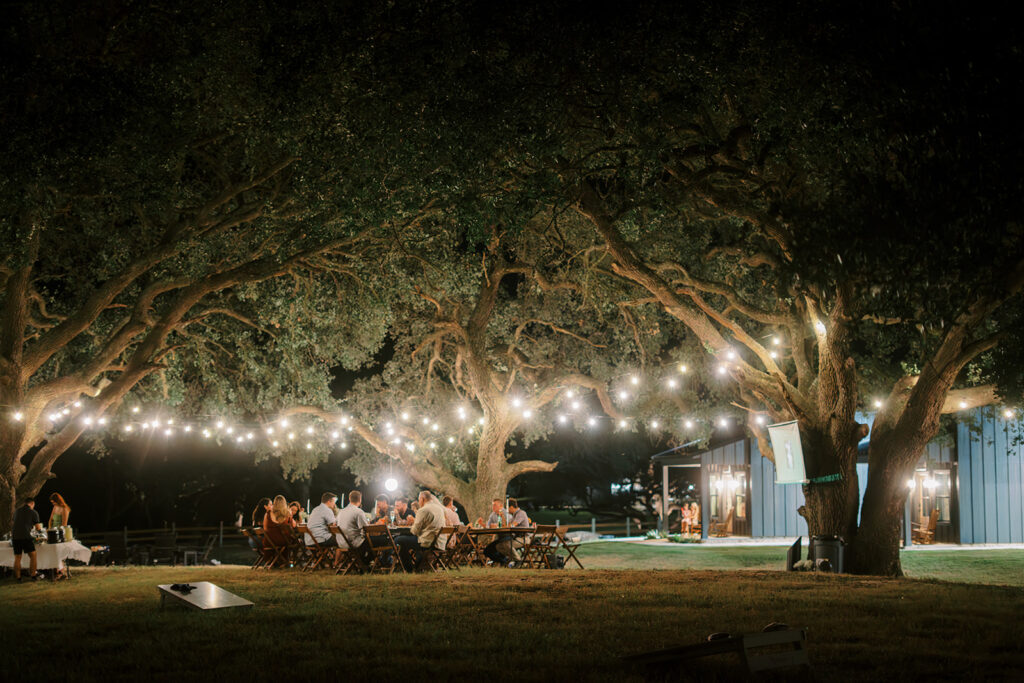 under the oaks, texas wedding venue, wedding rehearsal, texas bride, one more night, shiner texas, oak trees, bistro lights, dinner set up, outdoor dinner set up